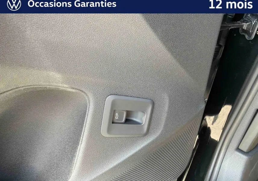Détail du bouton d'ouverture électrique du coffre sur la porte arrière droite d'un Volkswagen T-Roc noir.