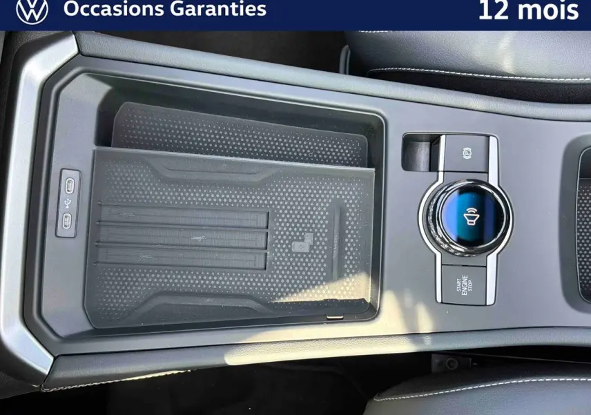 Vue rapprochée de la console centrale noire du Volkswagen T-Roc 2026 avec commande rotative et zone de recharge sans fil.