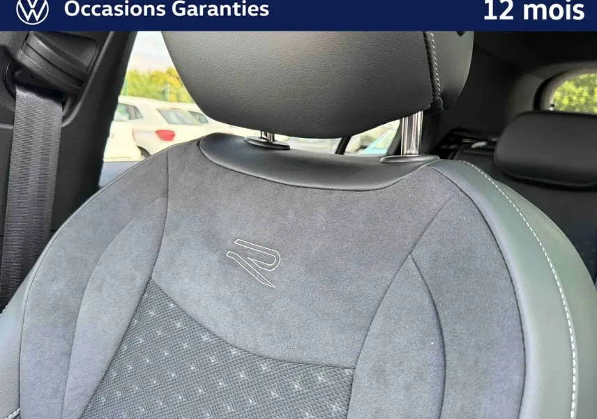 Gros plan sur le siège avant gris avec logo R brodé, intérieur du Volkswagen T-Roc 2026 visible en arrière-plan.