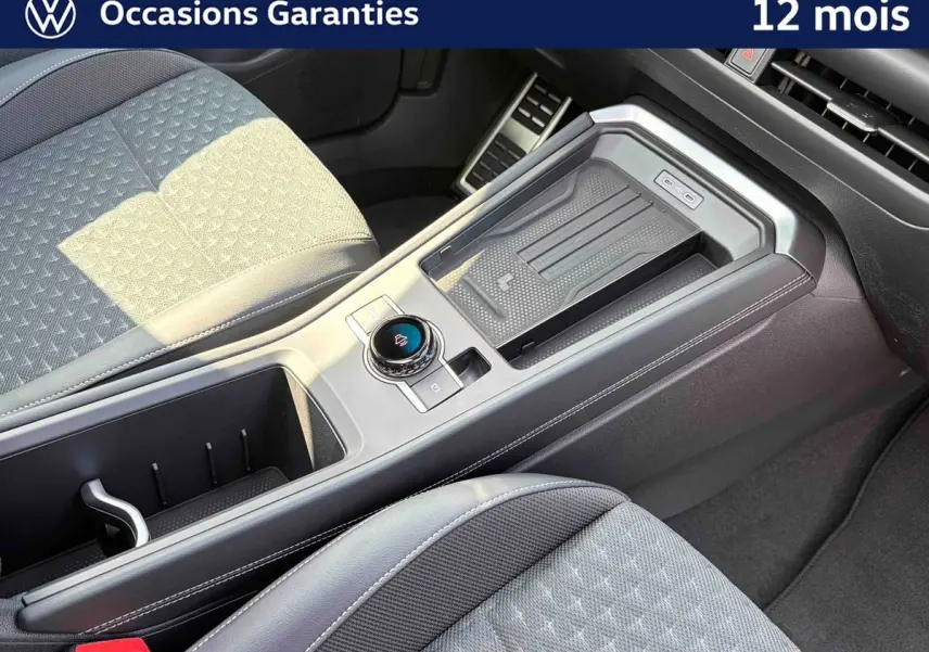 Vue intérieure rapprochée du console central et sièges avant gris du Volkswagen T-Roc noir, avec molette de sélection de vitesse.