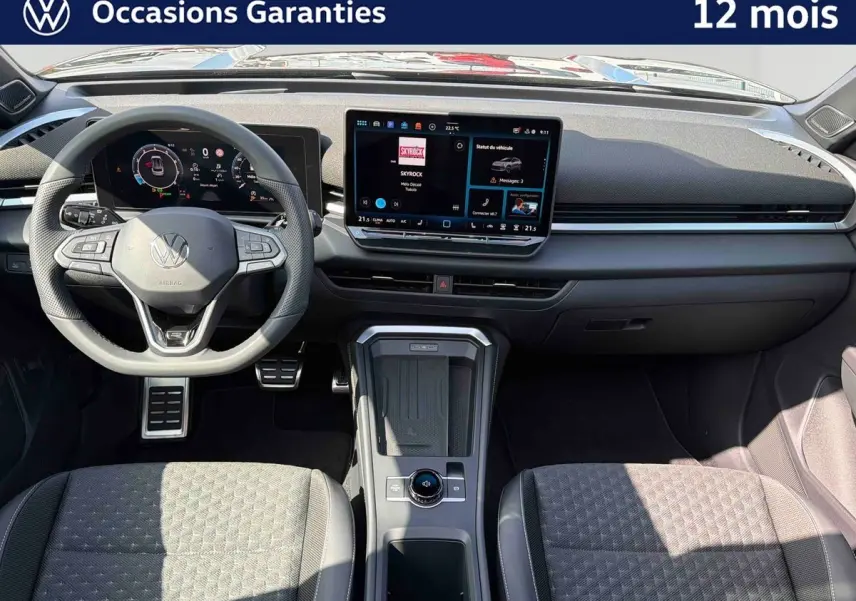 Vue intérieure avant du Volkswagen T-Roc noir, mettant en valeur le tableau de bord digital et la console centrale moderne.