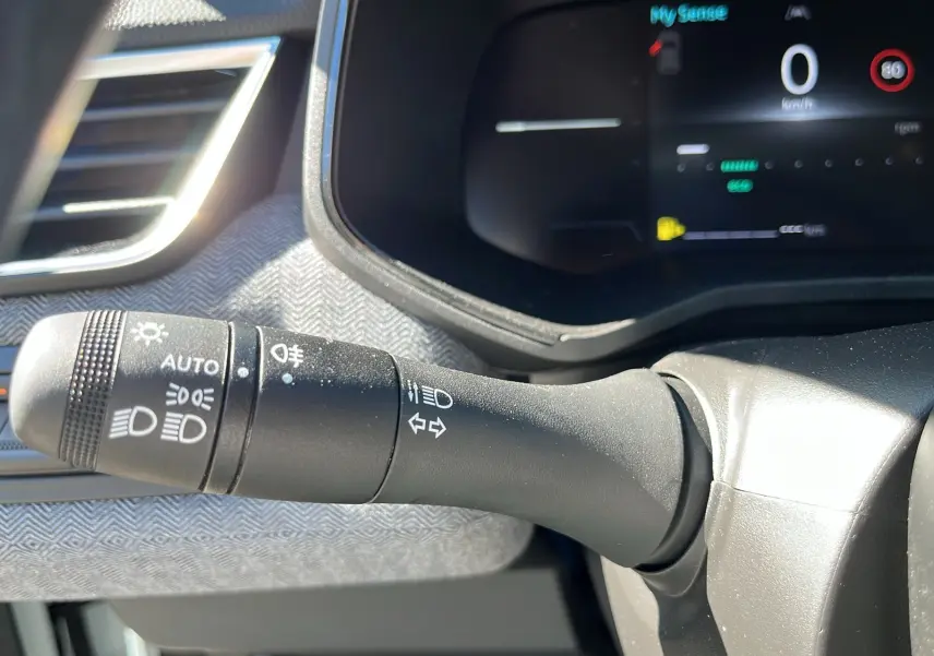 Gros plan sur la manette de commandes d'éclairage du tableau de bord d'une Renault Clio blanche 2025 V Facelift TCe 90 Techno.