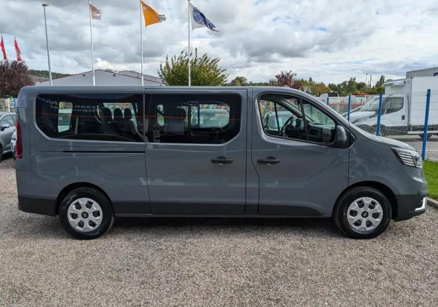 Profil latéral droit d'un Renault Trafic Fourgon gris Urban 2024 avec vitres teintées et jantes enjoliveurs 16 pouces.