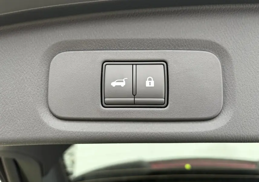 Boutons d'ouverture électrique du hayon et de verrouillage intégrés dans le hayon du Nissan Qashqai III gris foncé.