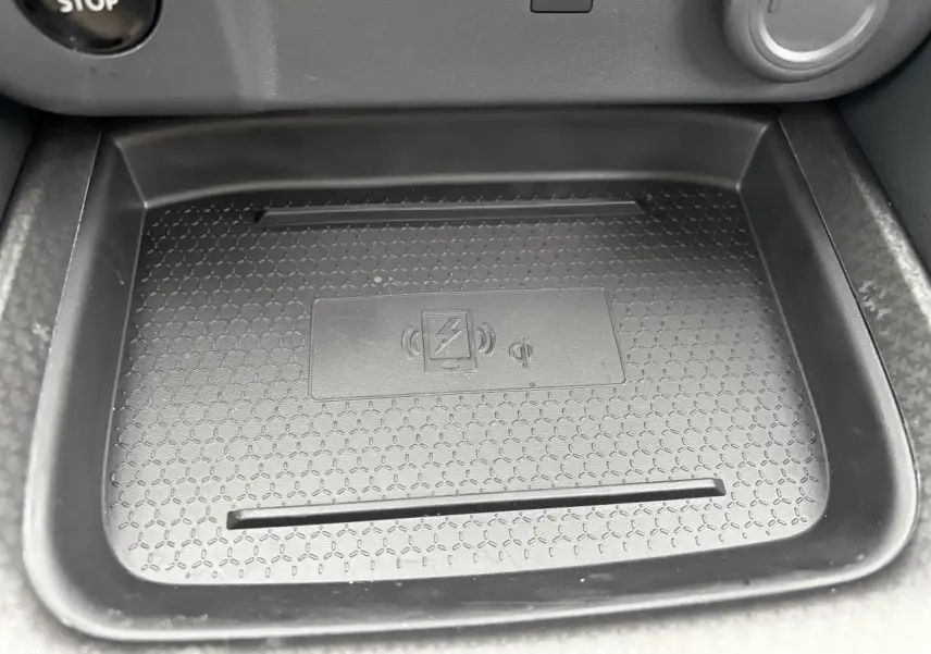 Gros plan sur le chargeur à induction noir dans la console centrale du Nissan Qashqai III gris foncé hybride 2025.