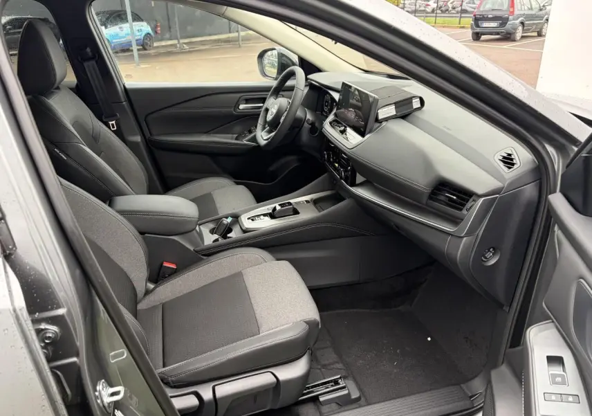 Intérieur côté conducteur du Nissan Qashqai 2025 gris foncé, avec sièges bi-matière, tableau de bord moderne et écran tactile.