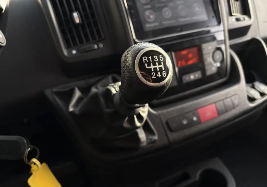 Gros plan sur le levier de vitesses manuel noir de l'Opel Movano Fourgon 2024 avec tableau de bord en arrière-plan.