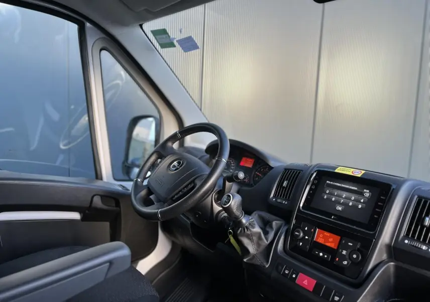 Vue intérieure côté conducteur de l'Opel Movano Fourgon blanc 2024, avec tableau de bord et écran tactile visibles.