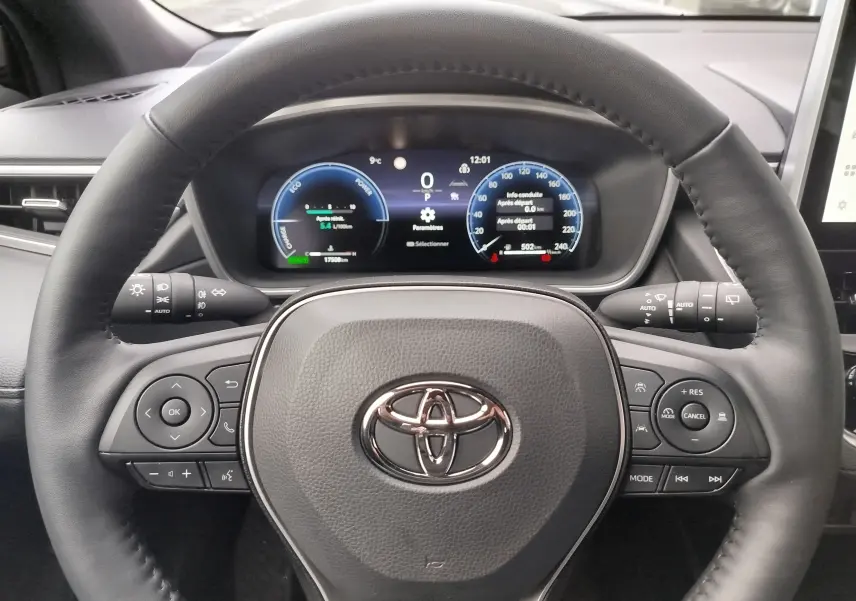 Vue rapprochée du volant noir et du tableau de bord numérique de la Toyota Corolla Cross 2025 hybride essence.