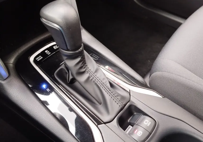 Gros plan sur la console centrale de la Toyota Corolla Cross 2025, levier de vitesse automatique en cuir noir et commandes électroniques.