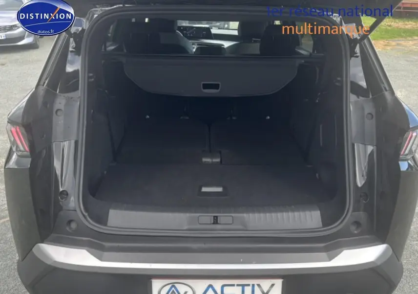 Coffre ouvert vu de l'arrière d'un Peugeot 5008 Hybrid 145 allure noir avec banquette rabattue et cache-bagages.