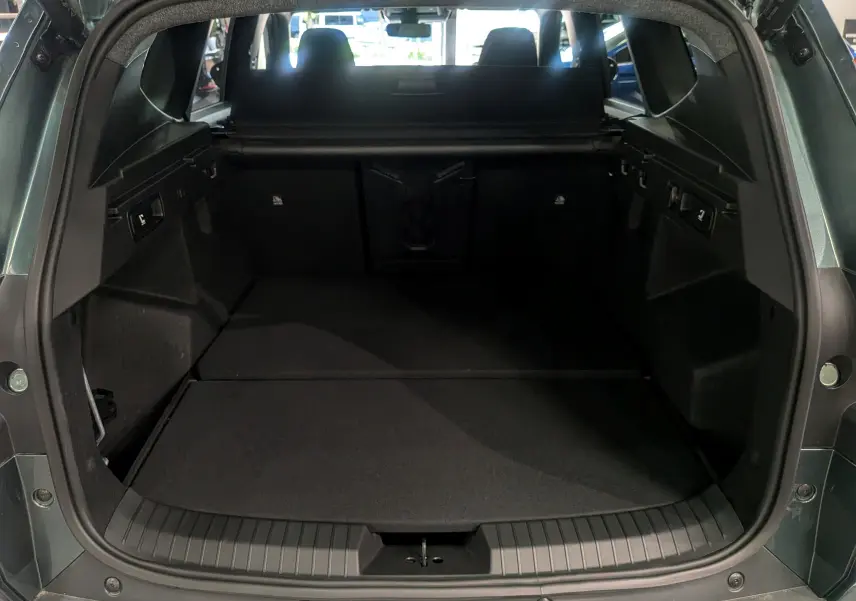 Vue arrière du coffre ouvert du Dacia Bigster Vert Cèdre, montrant un espace de chargement spacieux et noir.