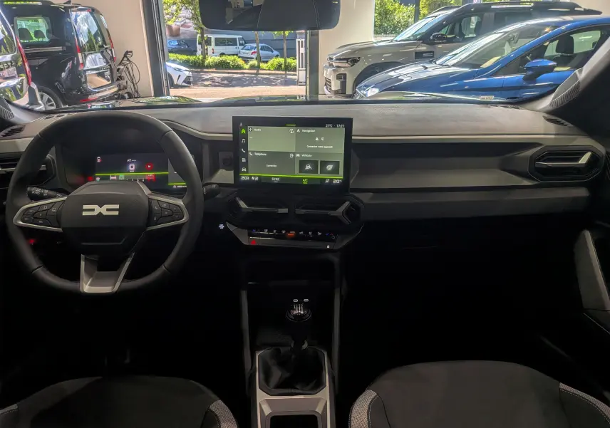 Vue intérieure frontale du tableau de bord du Dacia Bigster 2026, avec écran tactile central et volant multifonction noir.