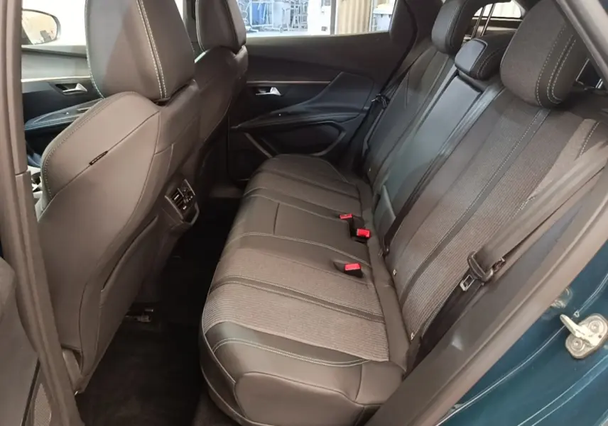Vue intérieure côté arrière droit du Peugeot 3008 bleu 2023, montrant la banquette arrière en tissu et cuir avec ceinture de sécurité.
