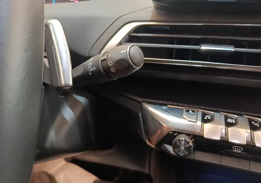 Détail intérieur du Peugeot 3008 hybride 2023 montrant la commande des essuie-glaces et les boutons de la console centrale.