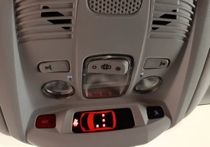 Vue rapprochée du plafonnier gris clair du Peugeot 3008 2023 avec boutons d’éclairage et alerte SOS rouge allumée.
