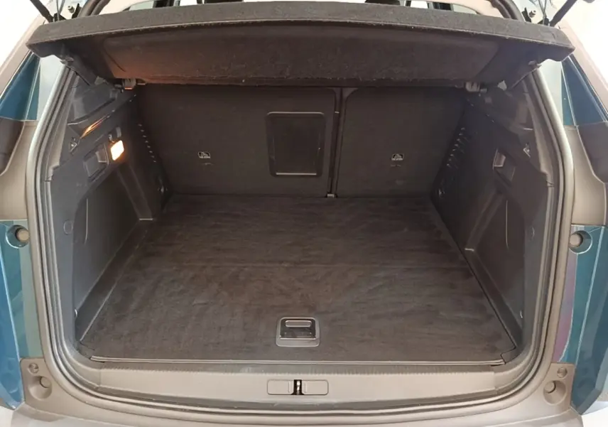 Coffre ouvert vu de l'arrière d'un Peugeot 3008 bleu, montrant l'espace de chargement et la banquette arrière rabattue.