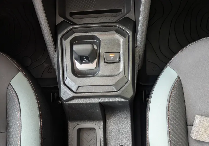Vue plongeante sur la console centrale du Dacia Duster Hybrid 155 Extreme, avec levier de vitesses et sièges bicolores gris et noir.