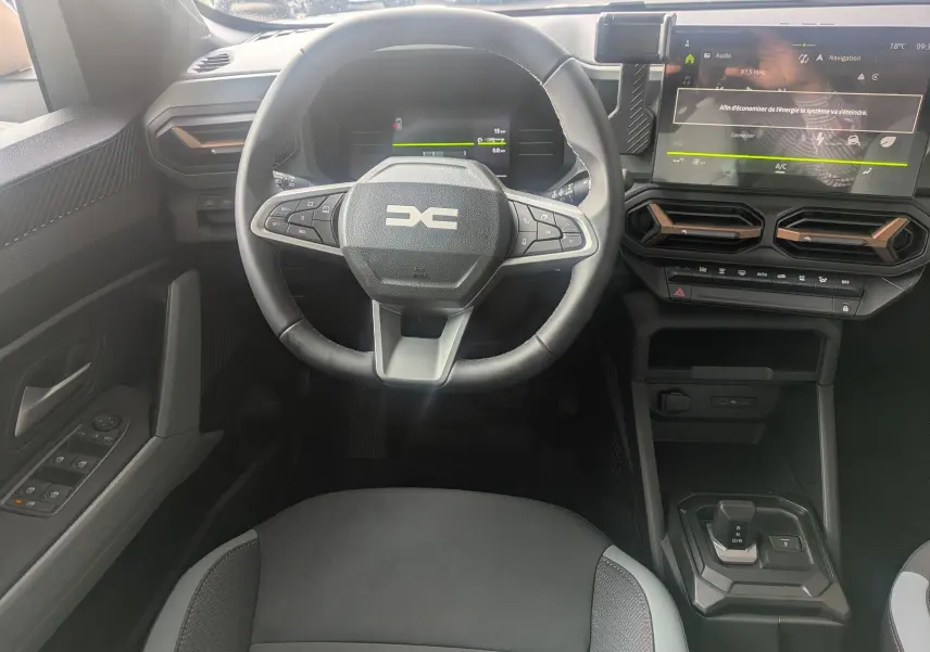 Vue intérieure centrée sur le volant et tableau de bord du Dacia Duster Hybrid 155 Extreme, avec écran tactile et commandes au volant.