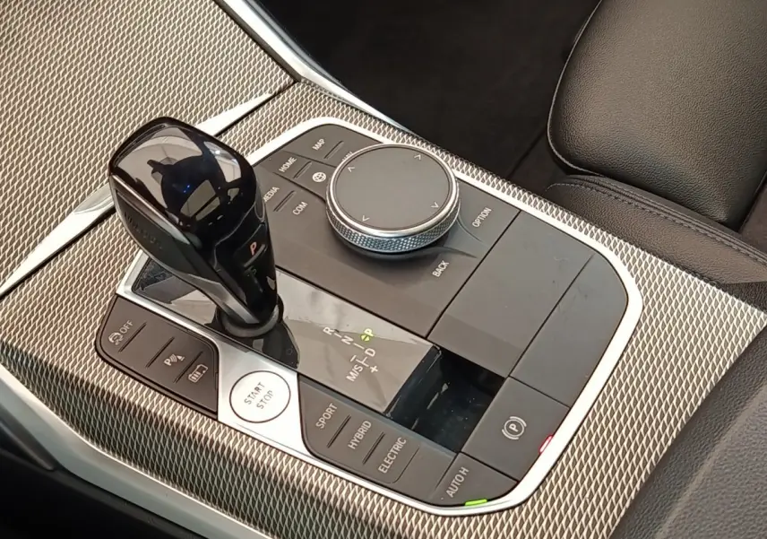 Gros plan sur la console centrale de la BMW Série 3 320e hybride, avec levier de vitesses et commandes mode de conduite.