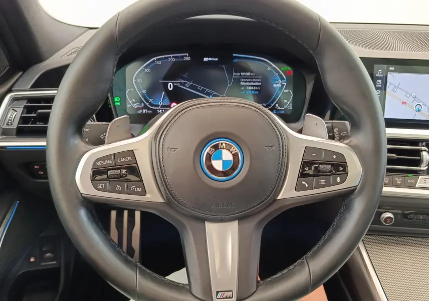 Vue rapprochée du volant cuir noir BMW M Sport avec tableau de bord digital et écran tactile de navigation.