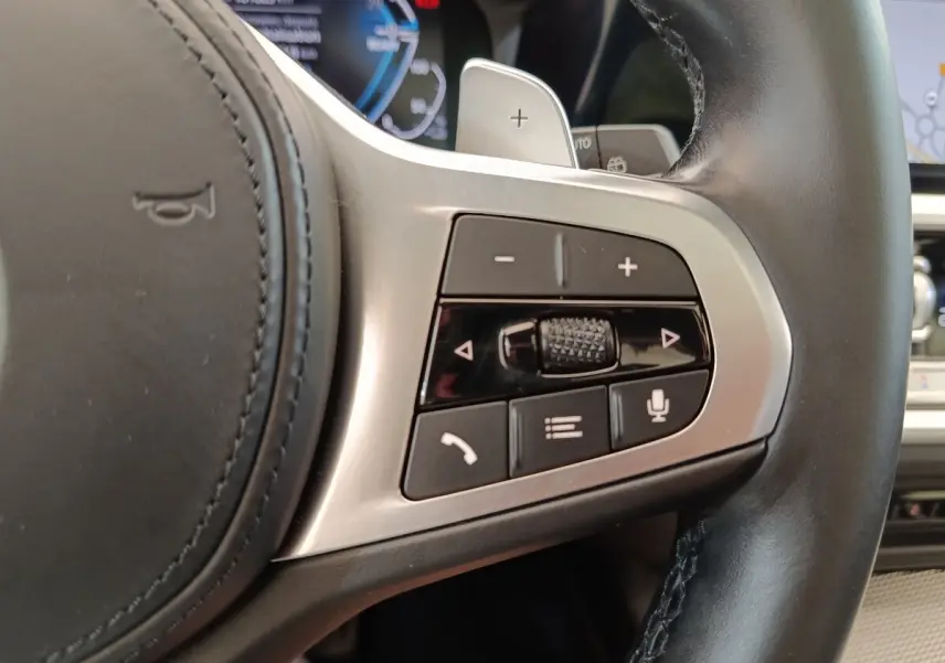 Gros plan sur les commandes multifonctions côté droit du volant cuir de la BMW Série 3 320e gris foncé hybride 2022.
