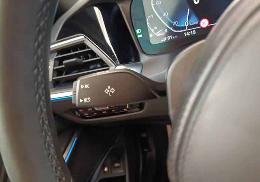 Détail du combiné d'instruments et commande au volant côté gauche dans l'habitacle d'une BMW Série 3 gris foncé hybride rechargeable.