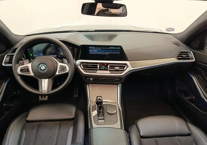 Vue intérieure avant de la BMW Série 3 320e M Sport 2022, tableau de bord moderne avec écran tactile et volant cuir noir.