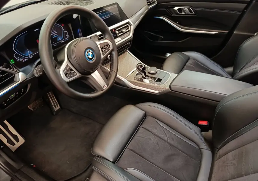 Vue intérieure côté conducteur de la BMW Série 3 320e M Sport 2022 avec tableau de bord digital et sellerie cuir noire.