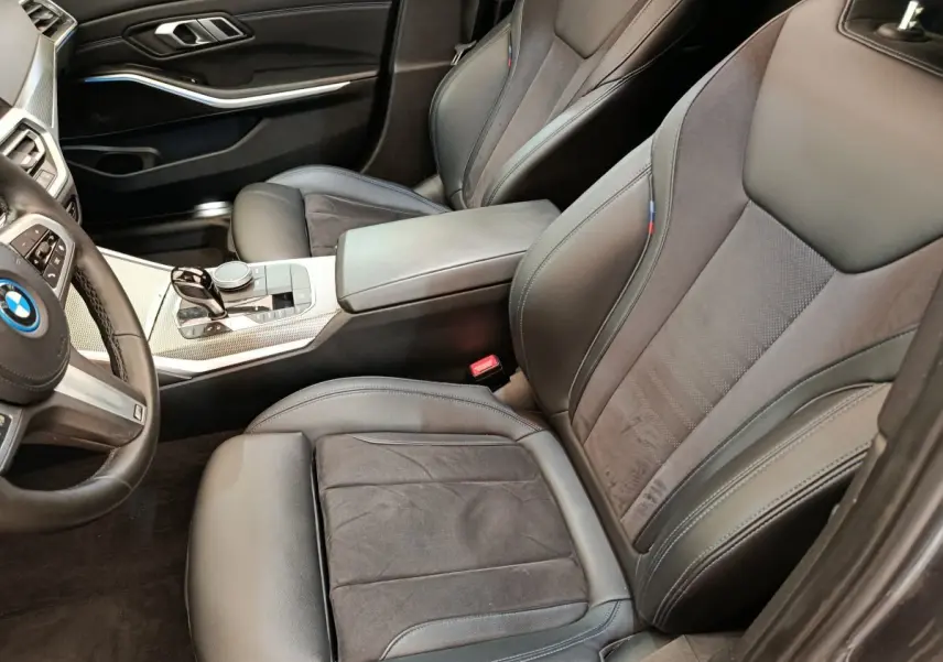 Vue intérieure côté conducteur de la BMW Série 3 320e gris foncé, sièges sport cuir et alcantara avec surpiqûres M tricolores.