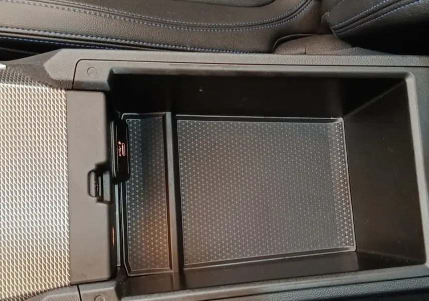 Gros plan sur la console centrale noire de la BMW Série 3 320e M Sport 2022, avec compartiment de rangement ouvert.