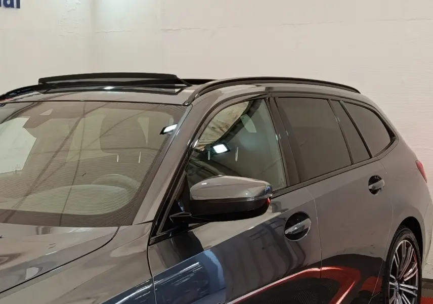 Vue de profil droit sur la BMW Série 3 320e M Sport hybride gris foncé avec toit ouvrant et jantes sport.