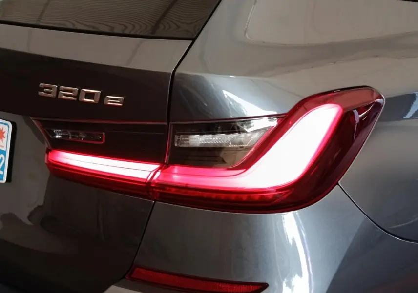 Gros plan sur l'arrière droit d'une BMW Série 3 320e gris foncé avec feu arrière LED allumé et logo visible.