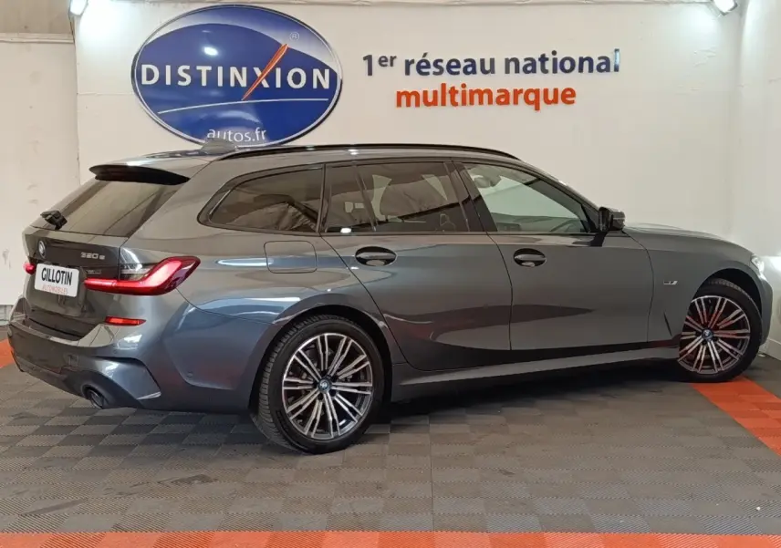 BMW Série 3 320e M Sport gris foncé vue de profil droit en break avec jantes alliage et feux arrière LED allumés.