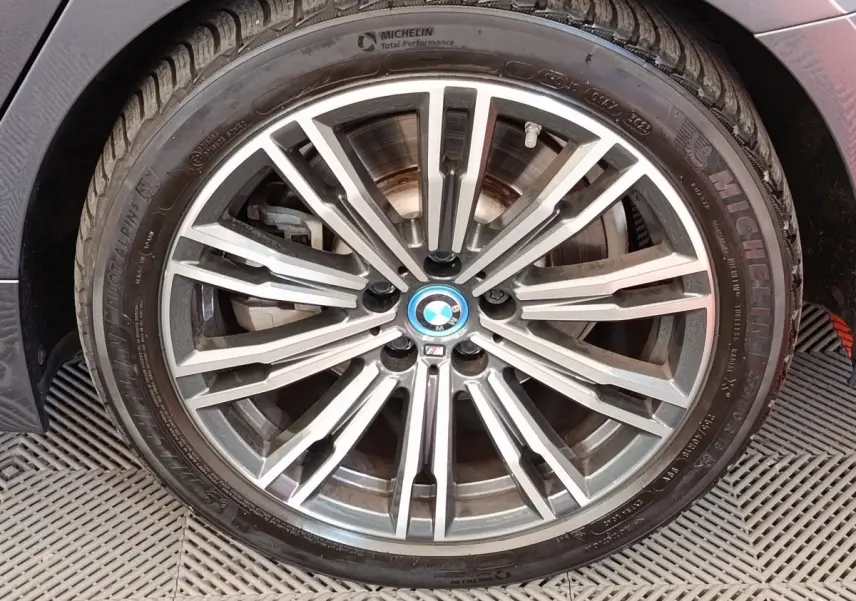 Gros plan sur la jante alliage BMW M Sport gris clair avec logo bleu au centre sur pneu Michelin.