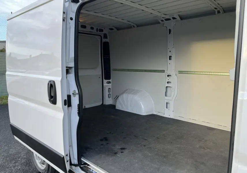 Vue latérale gauche d’un Opel Movano Fourgon blanc 2024 avec porte coulissante ouverte montrant l’intérieur vide et plancher noir.