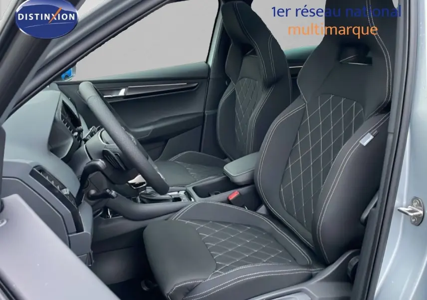 Vue intérieure côté conducteur du Skoda Karoq gris argent, sièges sport en tissu noir avec surpiqûres blanches.