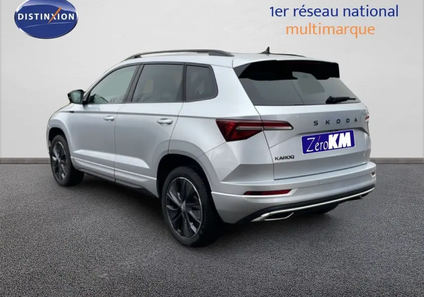 Vue 3/4 arrière droite d’un Skoda Karoq gris argent métal 2025 avec jantes bi-ton et toit noir.