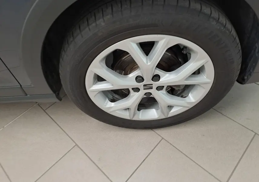 Gros plan sur la roue avant droite d'un SEAT Arona gris magnétique avec jante alliage argentée et logo central.