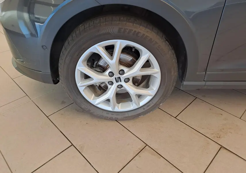 Gros plan sur la roue avant gauche du SEAT Arona gris magnétique, jante alliage argentée à 10 branches.