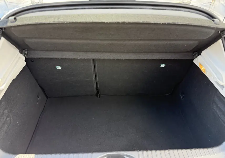 Vue intérieure du coffre ouvert d'une Renault Clio V gris, montrant un espace de rangement propre et bien fini.