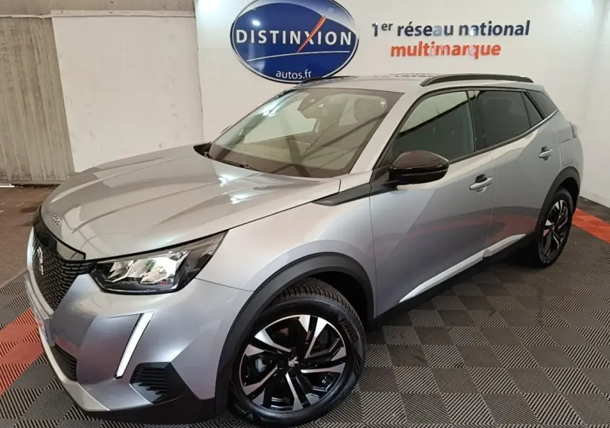 Peugeot 2008 gris clair vue 3/4 avant droit, avec jantes noires et rétroviseurs rabattables électriques.