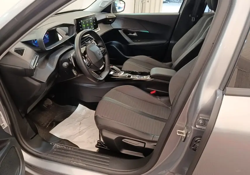 Intérieur avant droit d’un Peugeot 2008 gris clair 2022, avec tableau de bord numérique et écran tactile central.