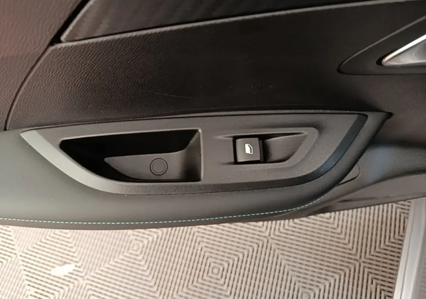 Détail de la poignée intérieure de porte côté gauche du Peugeot 2008 gris clair avec bouton de verrouillage.