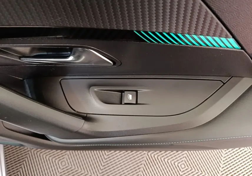 Détail de la porte côté gauche du Peugeot 2008 gris clair, avec bouton de commande de vitre et insert décoratif bleu.