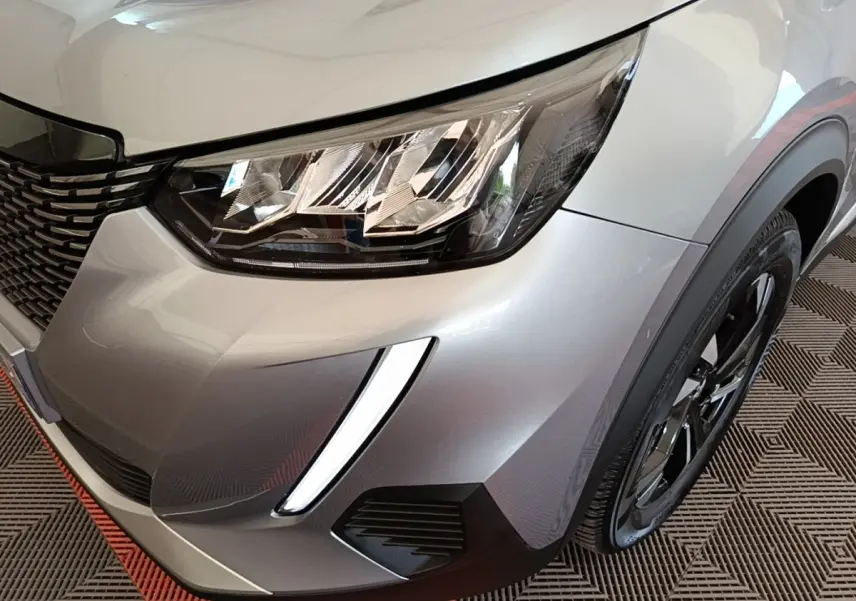 Gros plan sur l'avant droit gris clair du Peugeot 2008 2022, mettant en valeur le phare LED et la roue noire.