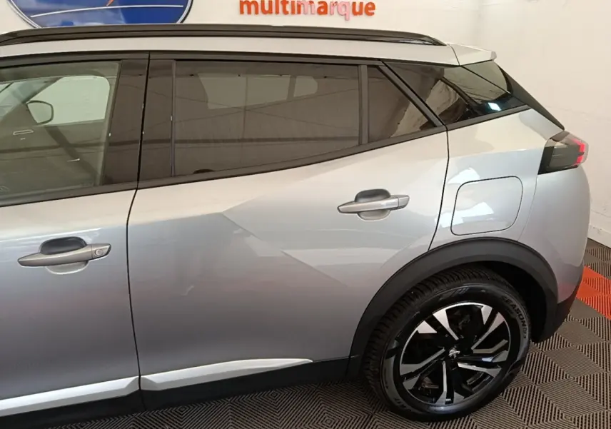 Vue latérale côté droit du Peugeot 2008 gris clair, mettant en valeur les vitres teintées et les jantes noires bicolores.