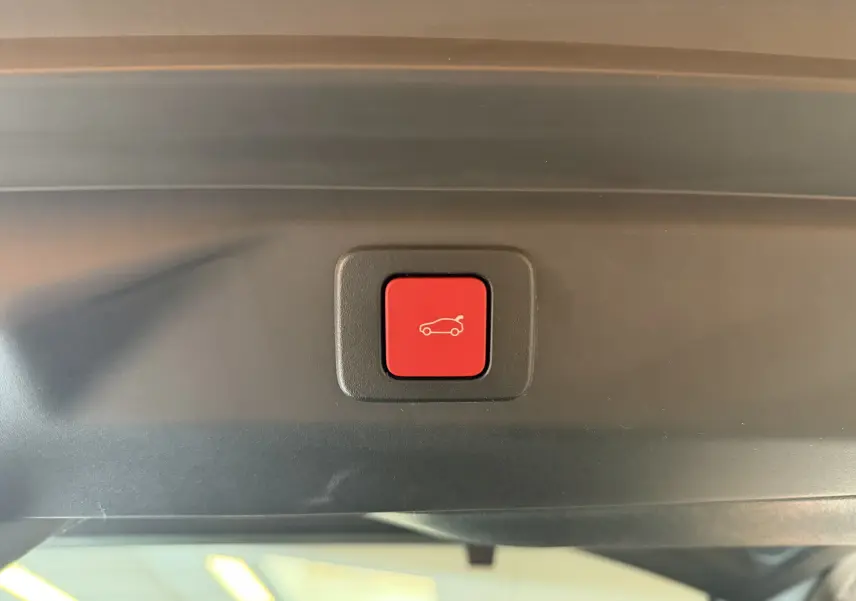 Bouton rouge d'ouverture électrique du hayon sur Peugeot 3008 Hybrid 145 GT, vue intérieure du coffre.