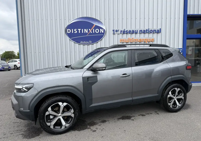 Profil côté gauche du Dacia Duster 1.6 Hybrid 140ch gris schiste avec jantes alliage et barres de toit noires.