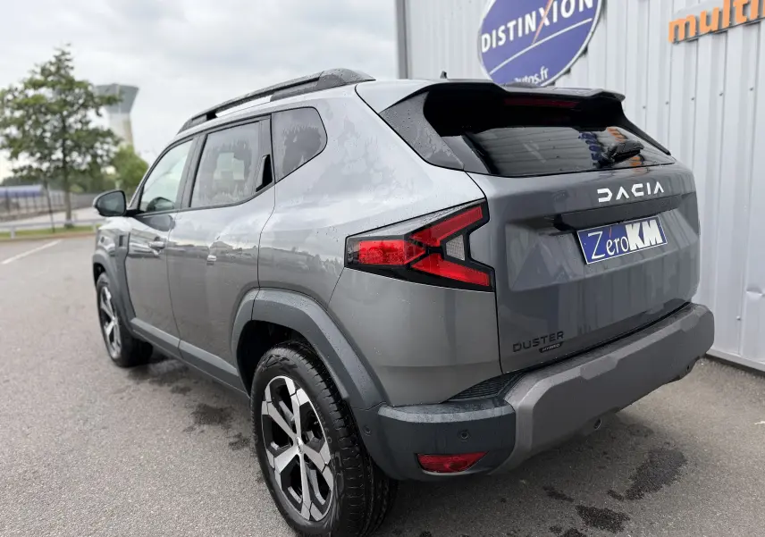 Vue 3/4 arrière droite du Dacia Duster 2025 gris schiste avec feux arrière LED et jantes alliage noires.